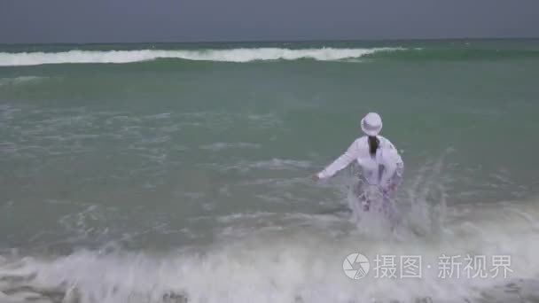 十几岁的女孩穿着衣服欢快地跳在波斯湾的海浪在迪拜的海滩上的股票录像视频