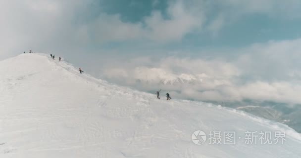 鸟瞰滑雪者  并准备越过山脊通过云