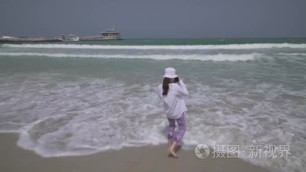 十几岁的女孩在迪拜的海滩上拍摄的波斯湾海浪的照片视频