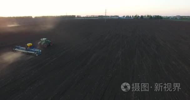 日落时拖拉机种植小麦的顶部视图