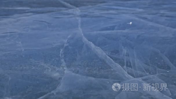 雪在冰面上飞过。雪花在贝加尔湖的冰上飞舞。冰是非常美丽的奇特独特的裂缝。雪在红色中闪闪发光。图片在日落。高对比度