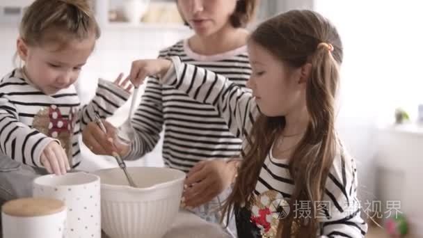 长黑发的女孩和她的妹妹是帮助他们的母亲在厨房