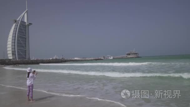 十几岁的女孩拍照的海浪在公共的朱美拉海滩上的波斯湾海岸, 迪拜股票录像视频