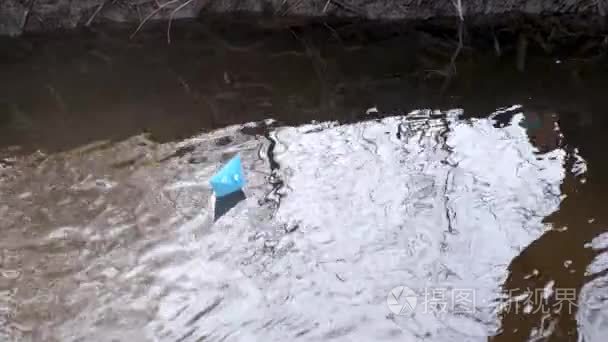 彩色纸的蓝色纸小船漂浮沿河岸视频