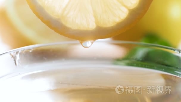 茶杯中柠檬片缓缓滴下的果汁滴的特写慢动作画面