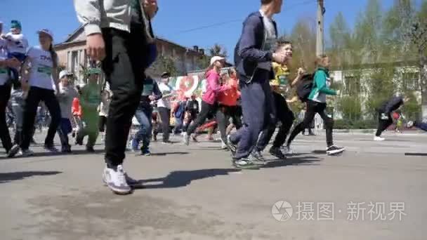 一群人和运动员跑在城市的道路上。慢动作