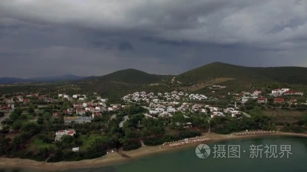 在阴天的希腊度假村上空飞越大海、海滩和小屋