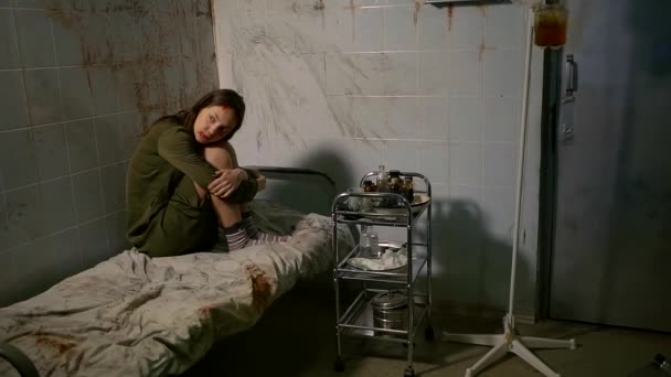 一个孤独的精神病妇女坐在床上, 她的腿抬起, 她看起来怪异和注定视频
