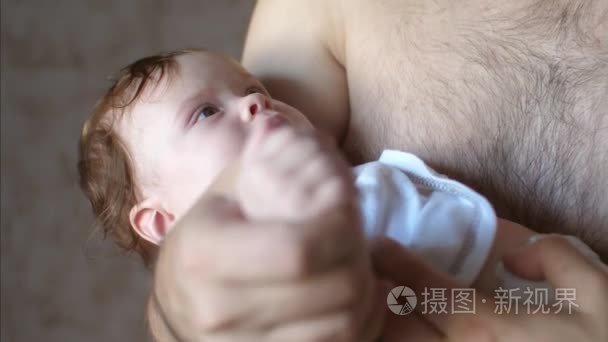 婴儿躺在他的父亲的怀抱和微笑视频