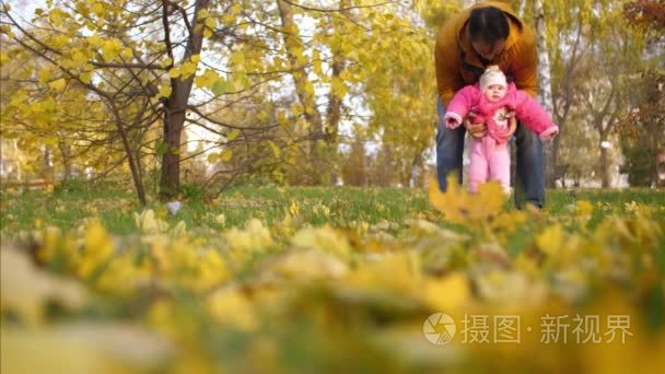 婴孩与他的父亲步行用他们的脚在秋天叶子