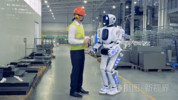 男性工厂工人远程控制机器人  他们一起走在一起