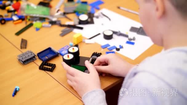 特写  儿童手拿着一个多彩多姿的小机器人  机器  组装从设计师。孩子们喜欢机器人  编程  建模