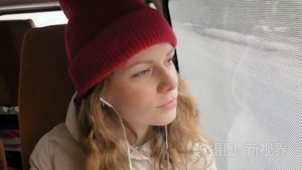 年轻快乐的女人乘公交车在悲伤的一天旅行。她向窗外望去