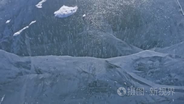 雪在冰面上飞过。雪花在贝加尔湖的冰上飞舞。冰是非常美丽的奇特独特的裂缝。雪在红色中闪闪发光。图片在日落。高对比度