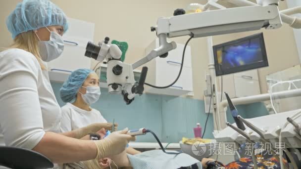 医生用特制的口腔数码微型相机来检查牙齿。在显示器上的牙医和病人看视频的牙齿  牙齿的问题。牙医用显微镜。牙医在现代牙科办公室