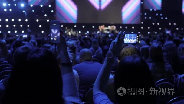 在音乐演唱会上, 人们用触摸式智能手机拍照, 现场直播体育场馆的心脏巡回表演。