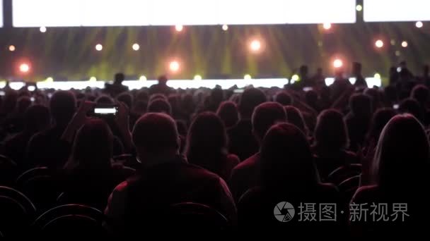 在音乐演唱会上  人们用触摸式智能手机拍照  现场直播体育场馆的心脏巡回表演。