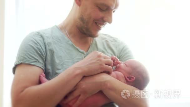 他父亲怀抱中的新生婴儿。孩子挥动着他的手。父亲温柔地吻他。父亲节。儿童节。亲子。单亲