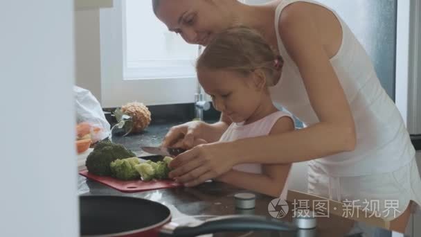年轻母亲教烹饪她的小女儿在家庭厨房