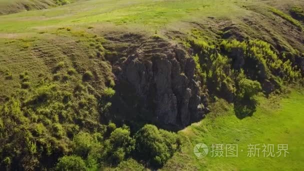 从山上下来的人鸟瞰。男人独自徒步沿着岩石悬崖。登山者在山上。在风景秀丽的绿色谷徒步旅行的人