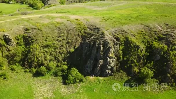 在风景如画的山谷  绿色的田野和丘陵  岩石峭壁和山脉  岩石日志和河流上空拍摄的空中镜头。春天和夏天季节自然概念的周末