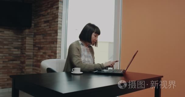 漂亮的女性在她的办公桌上使用她的信用卡  并从笔记本电脑订购的东西. 4 k