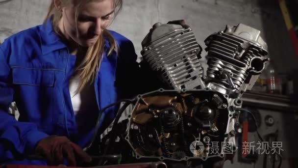 在车库工作的可爱的技工女孩与摩托车马达。妇女工作