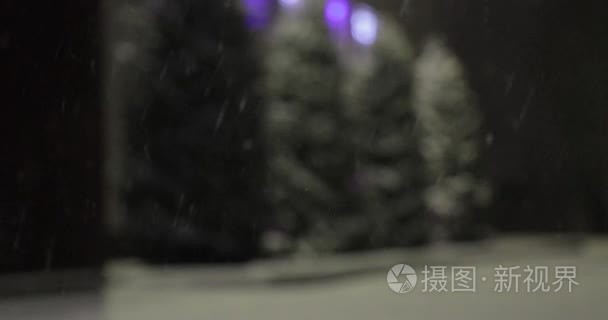 夜晚的雪在模糊的背景下落下视频