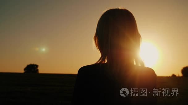 一个体贴的女人看夕阳  后景色。梦想与孤独的概念  展望未来