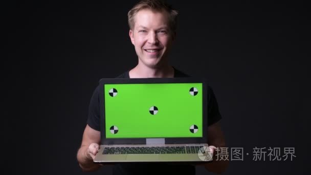 年轻英俊的人使用笔记本电脑与绿色屏幕色度键