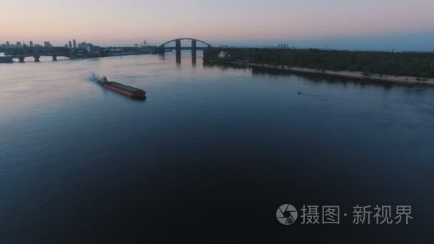 驳船在日落空中拍摄的城市港口附近的河流航行