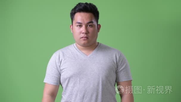 年轻英俊肥胖亚洲人反对绿色背景