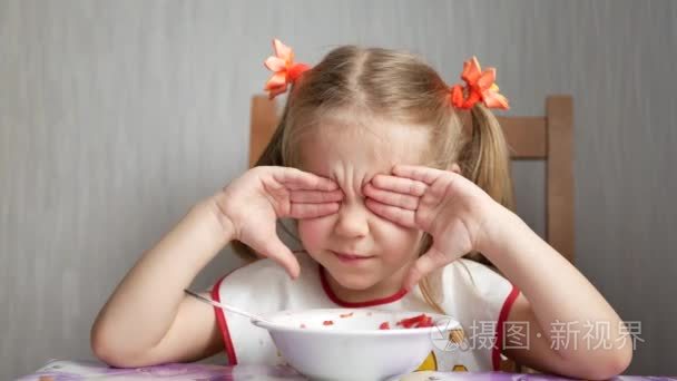 小女孩用白碗吃勺子