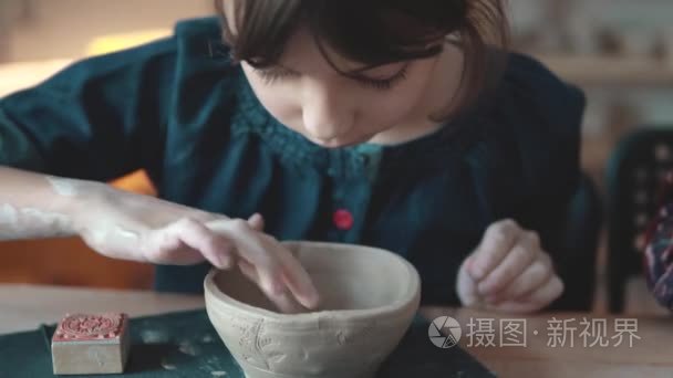 孩子正在做一盘粘土。陶器上的一课。小女孩用粘土印章制作图案