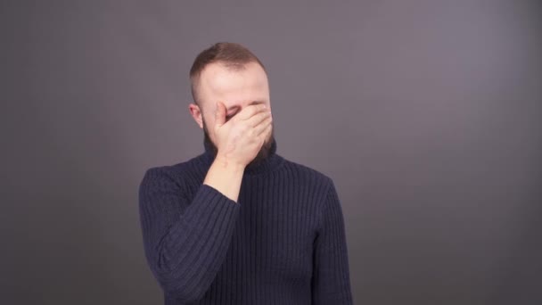 一个年轻哭泣的男人的肖像.隔离在灰色背景上