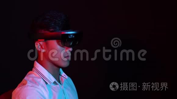 商人在黑暗的房间里试着戴上VR眼镜。 年轻亚洲男孩经历AR交流的肖像。 未来