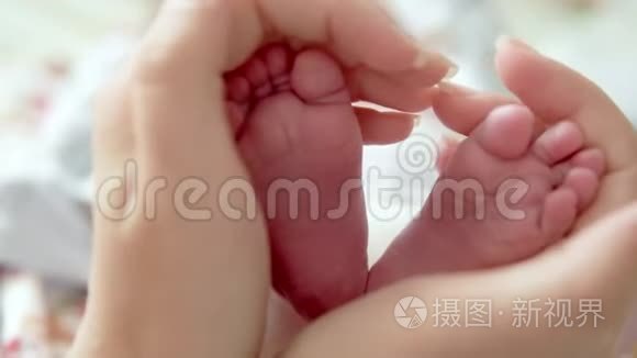 宝宝的脚在妈妈手里。 小新生婴儿脚在女性心脏整形的手特写。 妈妈和她的孩子。 快乐