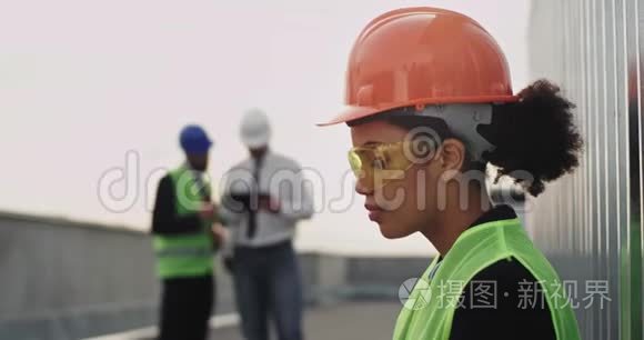 有魅力的年轻女工程师在建筑工地的屋顶上喝点水，她穿着一件