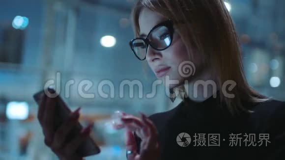 迷人的金发美女，心情愉快的眼镜，黑色的边缘和深色的衣服是在晚上的街道上。 她在附近