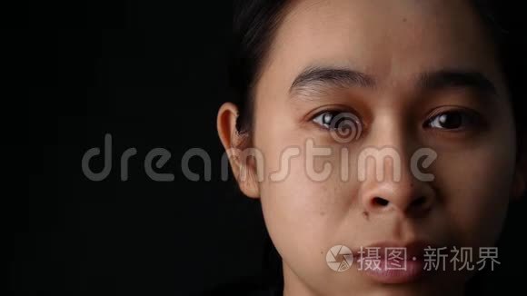 闭上女人的眼睛，在黑色的背景上微笑着哭泣