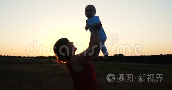 一个穿着紧身衣的中年女人在夕阳西下的田野里和孩子玩耍