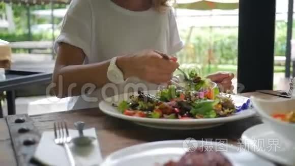 健康的生活方式女人在素食餐厅吃新鲜的绿色沙拉。 高清慢速运动。 泰国范甘。