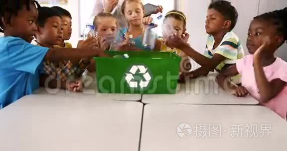 在教室里，孩子们把垃圾桶放在回收箱里