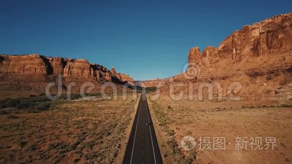 汽车沿美国沙漠公路直线行驶在大气岩石山峡谷山脊之间的空中镜头。