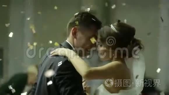 美丽的黑发新娘和英俊的新郎在婚礼上跳舞。 空中的纸屑.. 非常招标