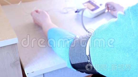 一位在家测量血压的老年妇女的手，一个光度计的袖口
