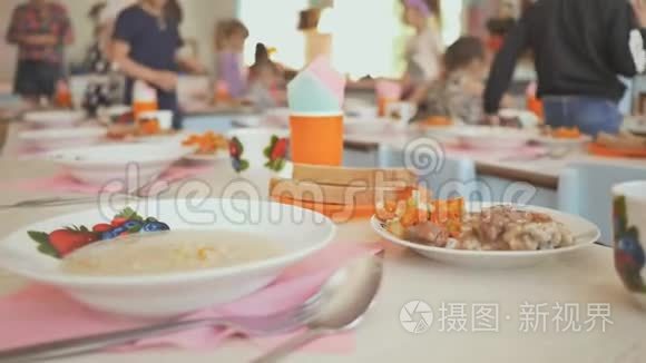 幼儿园午休准备.. 孩子们拿着熟食坐在桌子旁。 俄罗斯