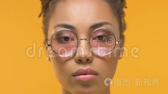 年轻的非洲妇女摘下眼镜看着镜头震惊皮肤科