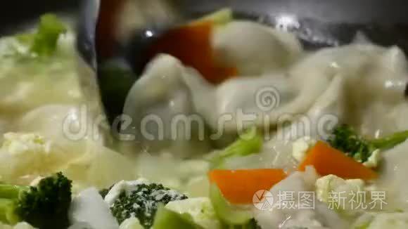 靠近一个女人在煎锅里煮蔬菜和饺子汤