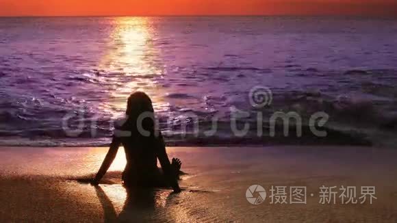 日落时海滩上神秘的剪影女孩